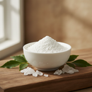 Pure camphor powder in a white ceramic bowl with camphor crystals and green leaves