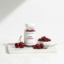 Nutridom Tart Cherry capsules on marble surface with fresh tart cherries