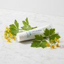 Unda Cheliderm homeopathic skin cream tube on marble surface with celandine botanical accents