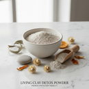 Living Clay Detox Powder — calcium bentonite clay in a ceramic bowl with wooden scoop and botanicals on white marble