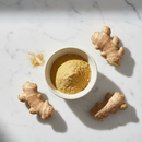 Ginger Root Powder — fine golden spice powder in ceramic bowl on white marble surface