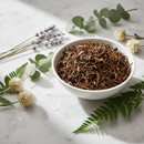 Oolong loose leaf tea in a white ceramic bowl on marble surface with botanical accents