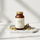 Genestra Herbal Calm supplement bottle on white marble surface with botanical accents