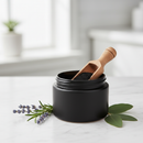Premium activated charcoal powder in a matte black jar on white marble surface with botanical accents
