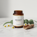Orange Naturals Kids Multi Vanilla 400g supplement jar on marble surface with botanical accents