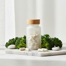 Genestra DIM supplement bottle on white marble surface with broccoli and kale botanical accents