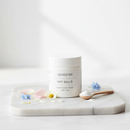 Genestra HMF Baby B infant probiotic powder jar on marble surface with soft botanical accents