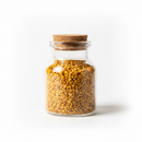 Bee pollen granules in a glass jar on white background