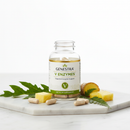 Genestra V Enzymes digestive enzyme supplement bottle on marble surface with botanical accents