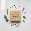 Neatly wrapped kraft parcel with natural twine and dried herb sprigs on a white marble surface
