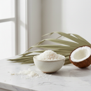 Organic shredded coconut in a ceramic bowl on white marble surface