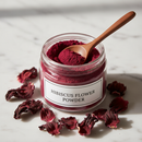 Hibiscus Flower Powder in a glass jar with dried hibiscus petals on a marble surface