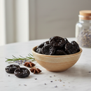 Premium pitted prunes in a ceramic bowl on white marble surface