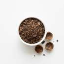 Dried black walnut hull cut and sifted in a white ceramic bowl on white background