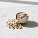 Organic hulled sunflower seeds in a ceramic apothecary bowl on white marble