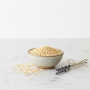 Organic quinoa flakes in a ceramic bowl on white marble surface