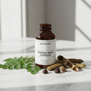 Nutridom Moringa Seed Capsules 120 caps on marble surface with moringa leaves