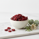 Organic dried cranberries in a ceramic bowl on white marble surface