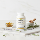 CanPrev D3 & K2 vitamin supplement bottle on white marble surface with botanical accents